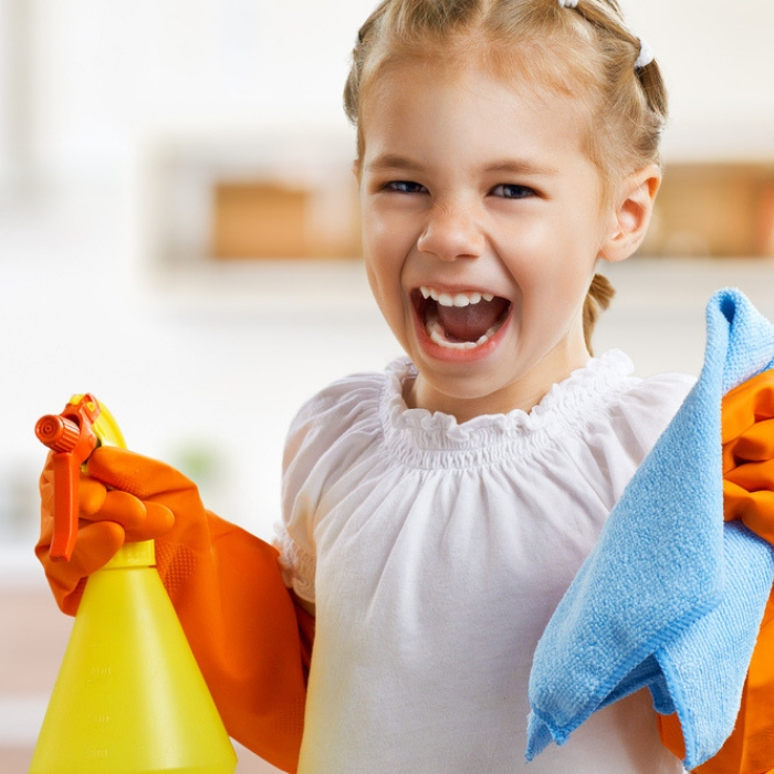 girl smiling while holding cleaning supplies